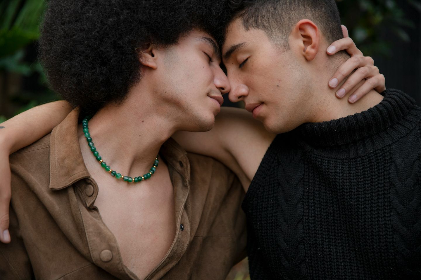 Two people embracing, foreheads touching and eyes closed, an arm wrapped around a neck.